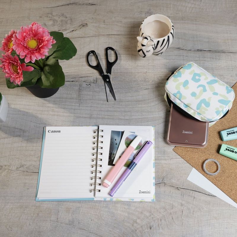 Canon Zoemini Mini-Fotodrucker, Roségold + Tagebuch + Tasche Drucker auf einem Schreibtisch mit Scheren