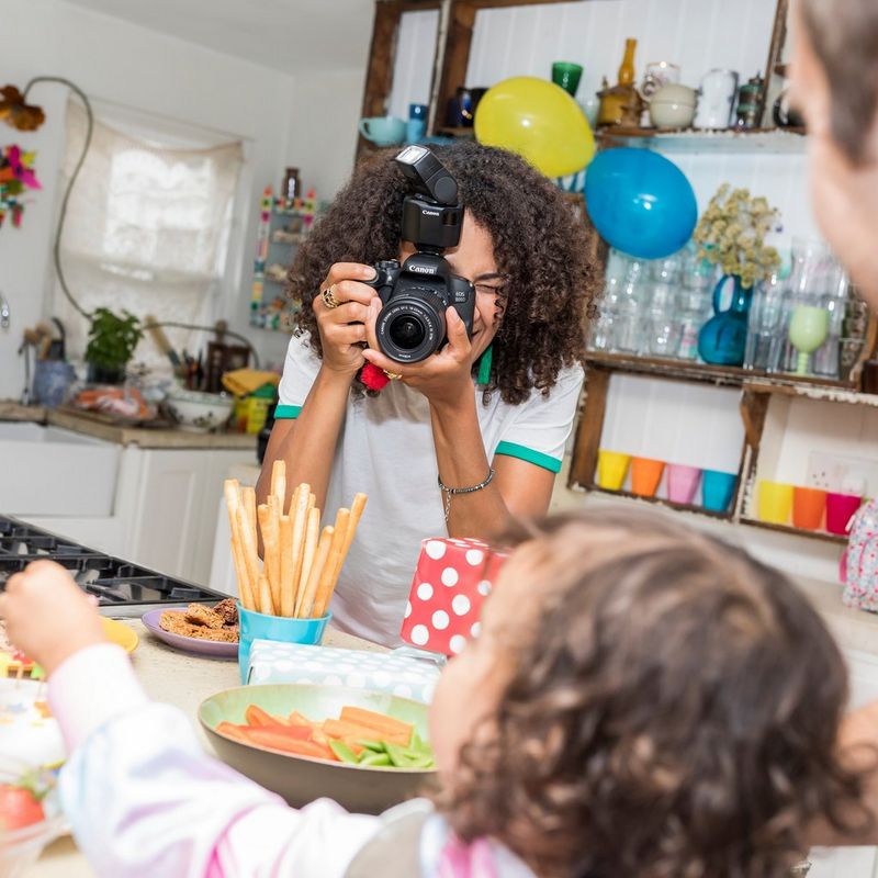 Canon Speedlite EL-100 Blitzgerät 0 Frau, die ein Foto eines Kindes aufnimmt