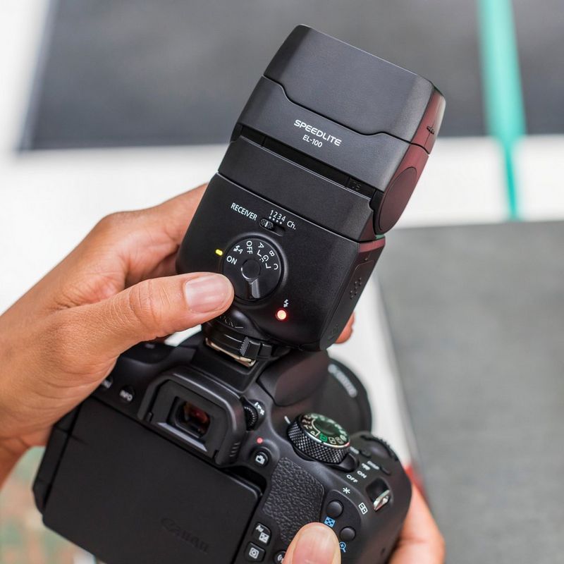 Canon Speedlite EL-100 Blitzgerät 0 Hand, die Blitztasten drückt