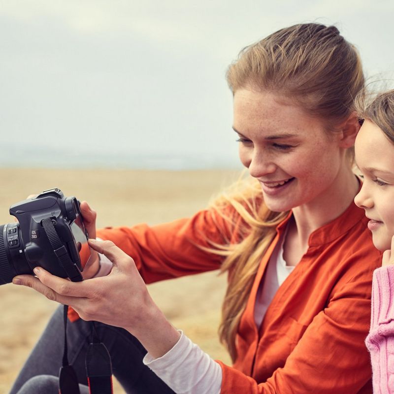 Canon EOS 250D Gehäuse, Silber + EF-S 18-55mm f/4-5.6 IS STM Objektiv Frau, die eine Kamera hält
