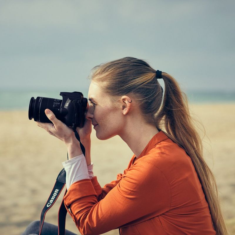 Canon EOS 250D Gehäuse, Silber + EF-S 18-55mm f/4-5.6 IS STM Objektiv Frau, die eine Kamera hält, um ein Foto zu machen