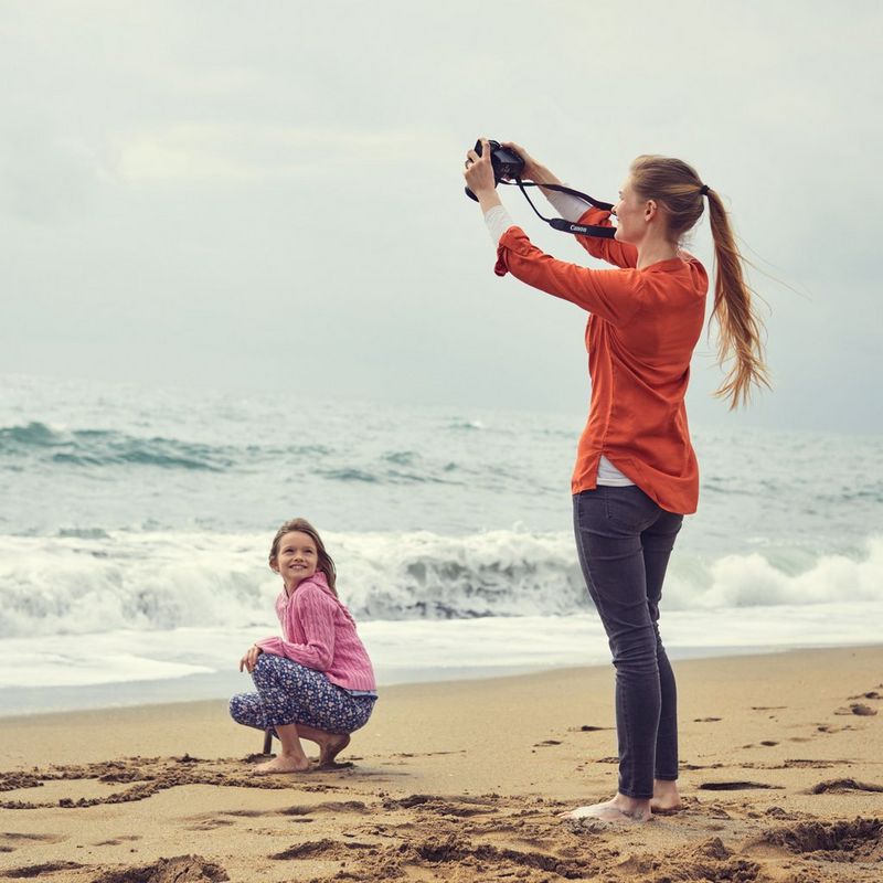 Canon EOS 250D Gehäuse, Silber + EF-S 18-55mm f/4-5.6 IS STM Objektiv Frau, die ein Foto eines Mädchens am Strand aufnimmt