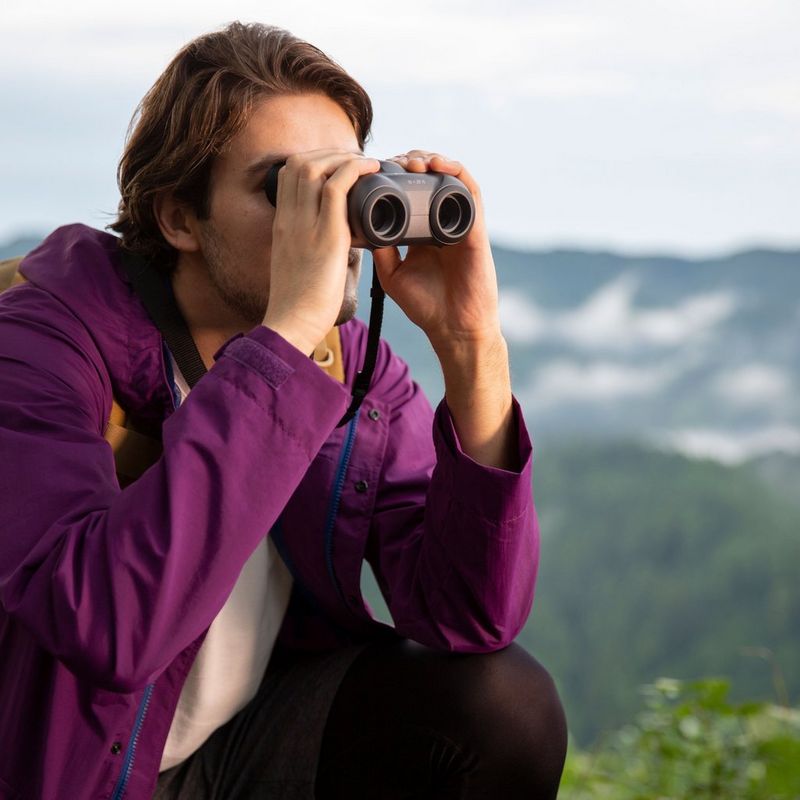 Canon 10x20 IS Fernglas Mann, der sein Fernglas in den Bergen verwendet