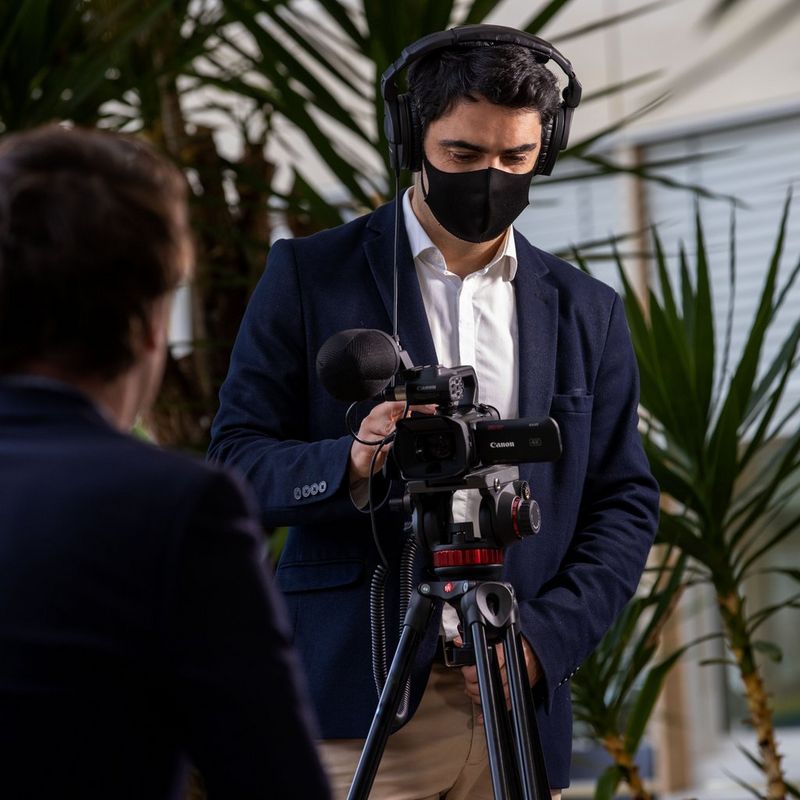 Canon XA45 Camcorder Mann, der mit einem Camcorder auf einem Stativ filmt