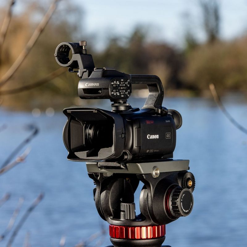 Canon XA45 Camcorder Vorderansicht von links auf einem Stativ vor einem See
