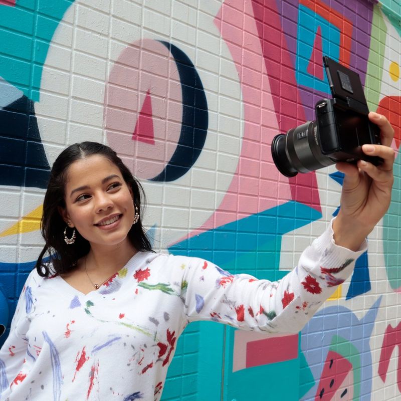 Canon EOS M200 Gehäuse, Schwarz + EF-M 15-45mm + EF-M 55-200mm Eine Frau, die ein Foto an einer Wand aufnimmt