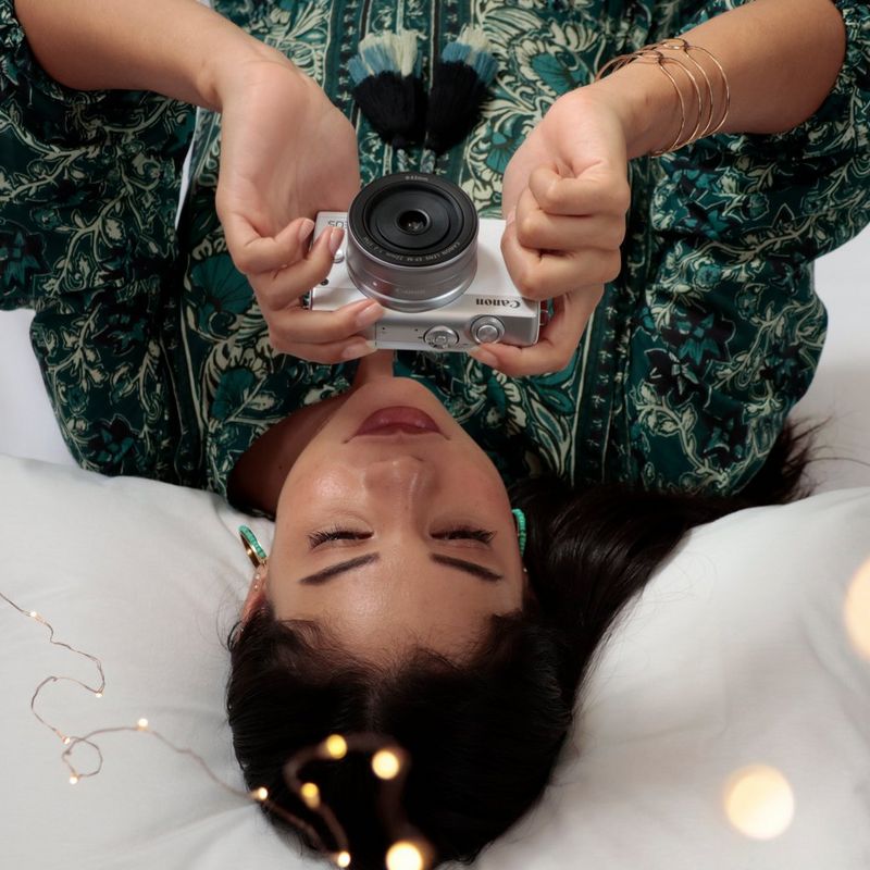 Canon EOS M200 Gehäuse, Weiß + EF-M 15-45mm, Silber 0 Eine Frau, die im Liegen auf das Kameradisplay schaut