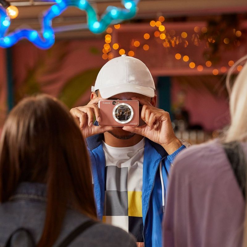 Canon Zoemini S Sofortbildkamera und Mini-Fotodrucker, Roségold Mann mit Kappe, der ein Foto knipst