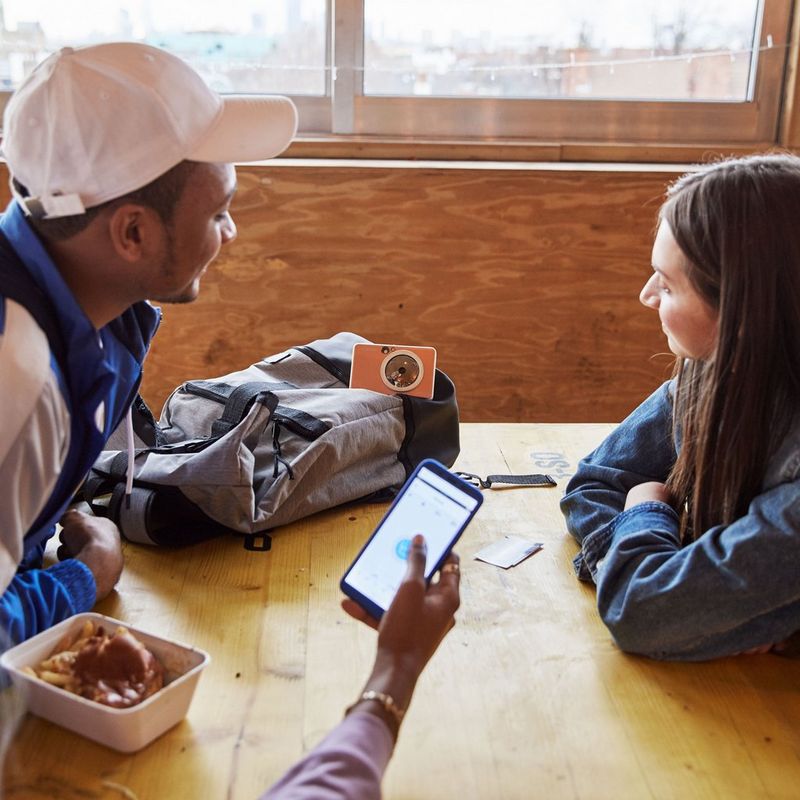 Canon Zoemini S Sofortbildkamera und Mini-Fotodrucker, Roségold Drucker auf Tasche mit 2 Personen, die ihn betrachten