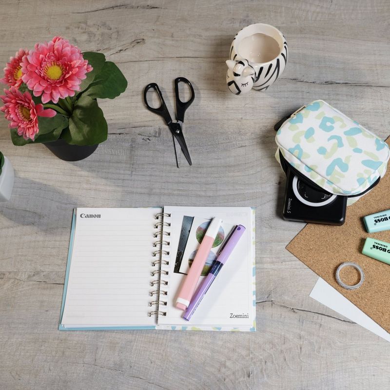 Canon Zoemini S mobile Sofortbildkamera mit Mini-Fotodrucker, Mattschwarz + Tagebuch + Tasche Drucker auf einem Schreibtisch mit Scheren