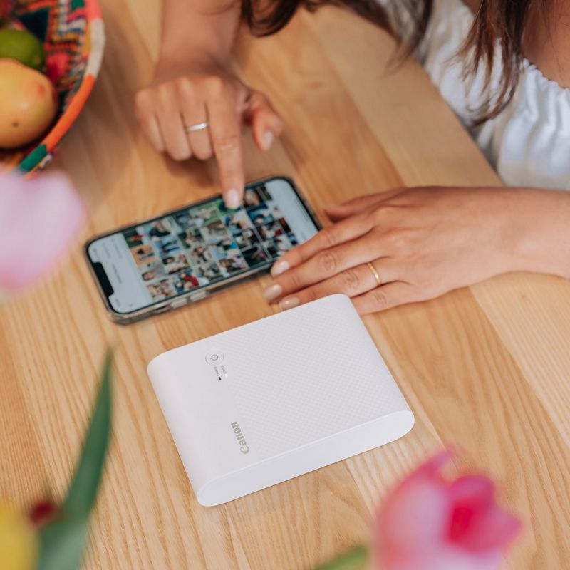 Canon SELPHY SQUARE QX10 mobiler WLAN-Farbfotodrucker, Premium-Kit, Weiß Hand, die über ein Handy das Produkt steuert