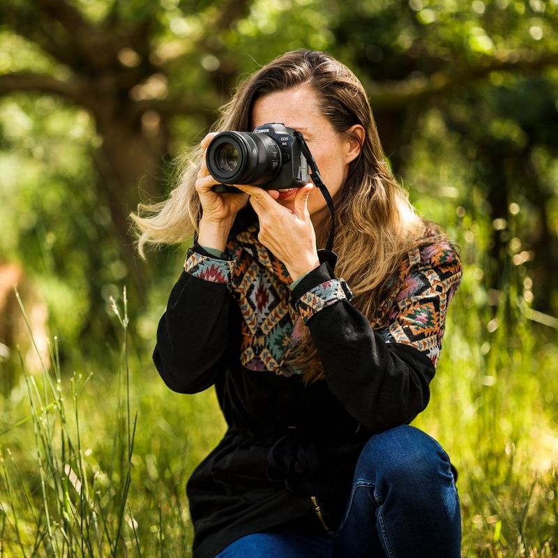 Canon RF 85mm F2 Macro IS STM Objektiv Eine Frau, die eine Kamera vor ihr Gesicht hält