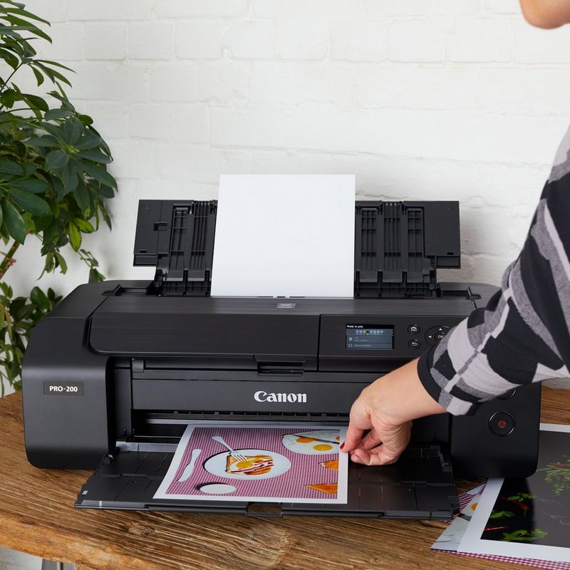 Canon PIXMA PRO-200 A3 Plus Drahtloser Foto-Farbdrucker Produkt Vorderansicht mit einer Person, die das Foto aus dem Papierfach entnimmt
