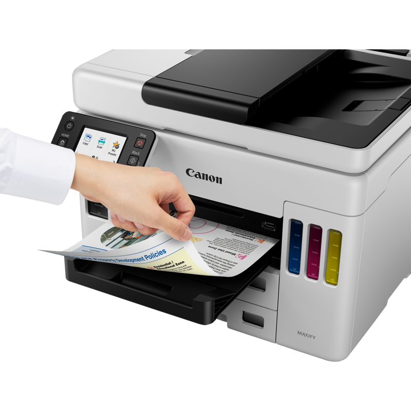 Canon MAXIFY GX7050 MegaTank Farb-Tintenstrahl-Multifunktionssystem mit WLAN und nachfüllbaren Tintentanks Produkt Schrägansicht von vorne mit einer Person, die das Foto aus dem Papierfach entnimmt