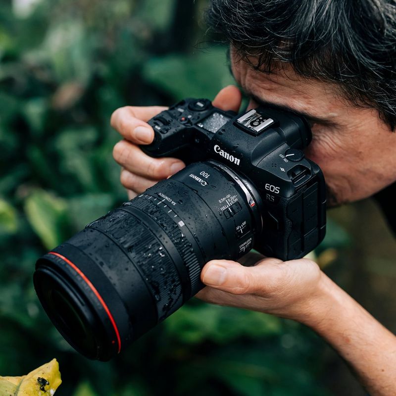 Canon RF 100mm F2.8 L MACRO IS USM Objektiv Ein Mann, der eine Kamera vor sein Gesicht hält