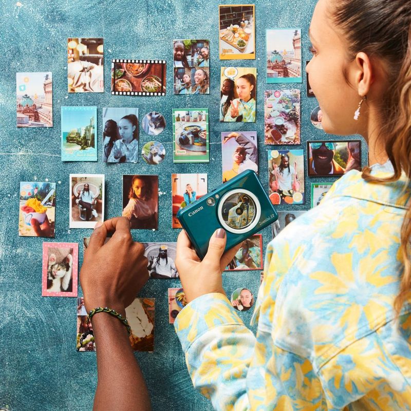 Canon Zoemini S2 Sofortbildkamera mit Mini-Fotodrucker, Aquamarin + Tagebuch + Tasche Paar sortiert Ausdrucke an einer Wand