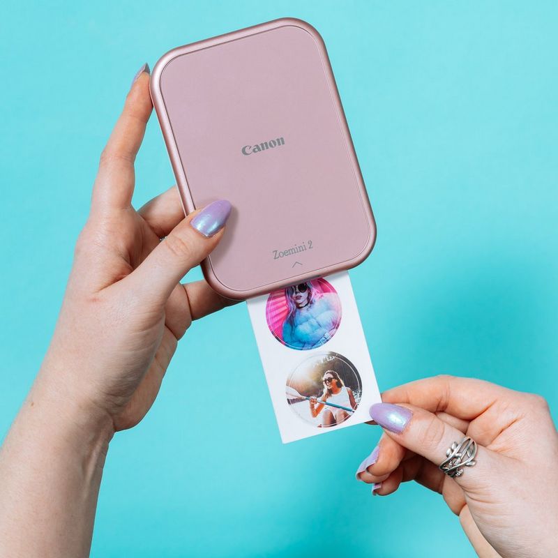 Canon ZINK™ Fotopapier mit vorgestanzten runden Stickern mit 33 mm Durchmesser, 20 Blatt Produkt Bei Verwendung auf einem Tisch neben einem Canon Zoemini Drucker und einem Smartphone