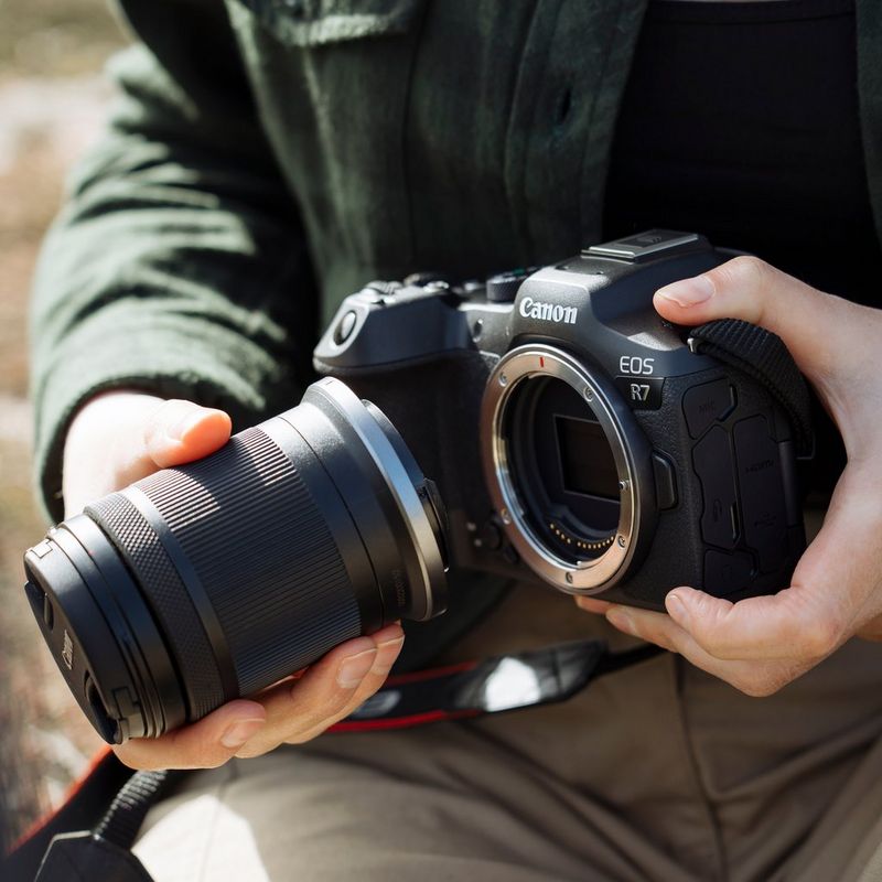 Canon EOS R7 spiegellose Kamera (Gehäuse) + RF-S 18-150mm F3.5-6.3 IS STM Objektiv + RF-S 10-18mm F4.5-6.3 IS STM Objektiv Eine Person, die ein Objektiv an einer Kamera anbringt