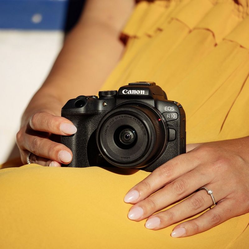 Canon EOS R10 spiegellose Kamera und RF-S 18-150mm F3.5-6.3 IS STM Objektiv Lifestyle Kamera auf dem Bein einer Frau