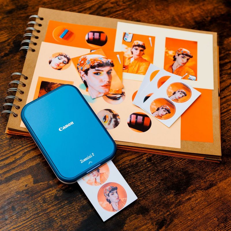 Canon Zoemini 2 mobiler Farb-Fotodrucker, Marineblau Produkt neben einem Fotoalbum mit zusätzlichen Fotos