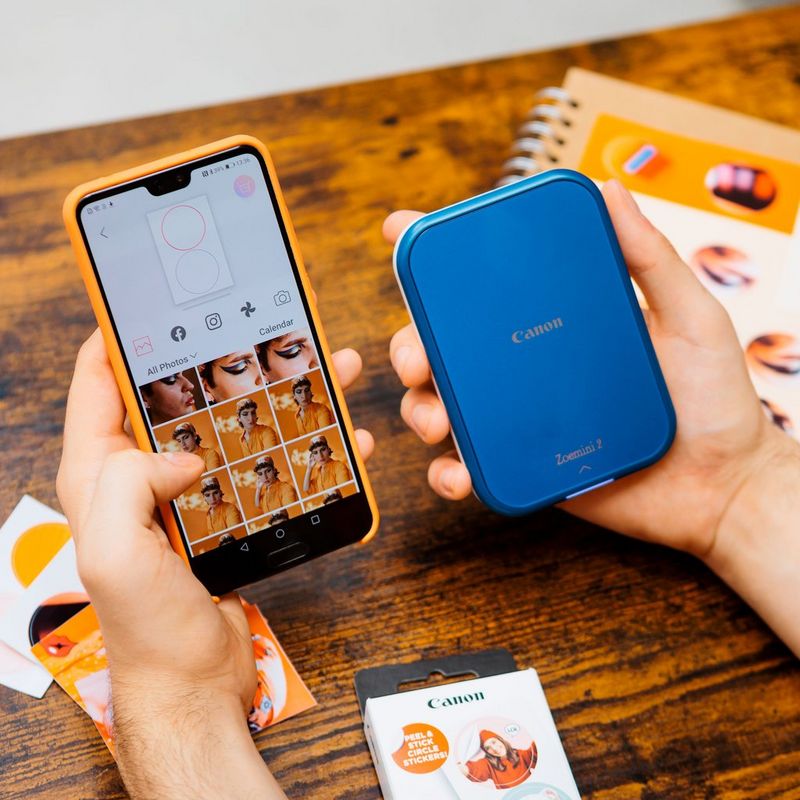 Canon Zoemini 2 mobiler Farb-Fotodrucker, Marineblau Frau bedient ein Telefon mit dem Produkt in der Hand