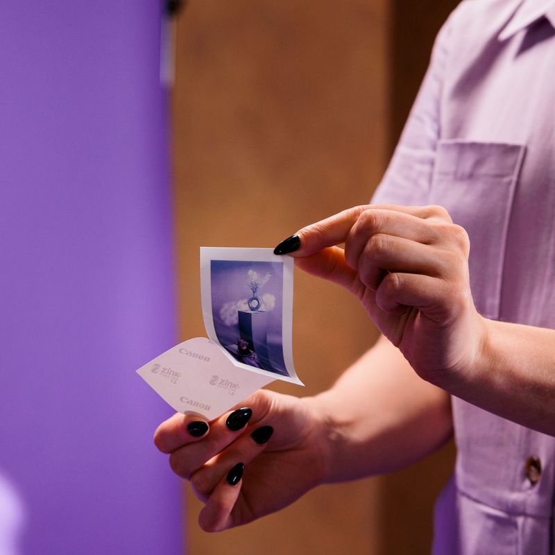 Canon Zoemini 2 mobiler Farb-Fotodrucker, Marineblau Frau entfernt den rückseitigen Sticker von einem Foto