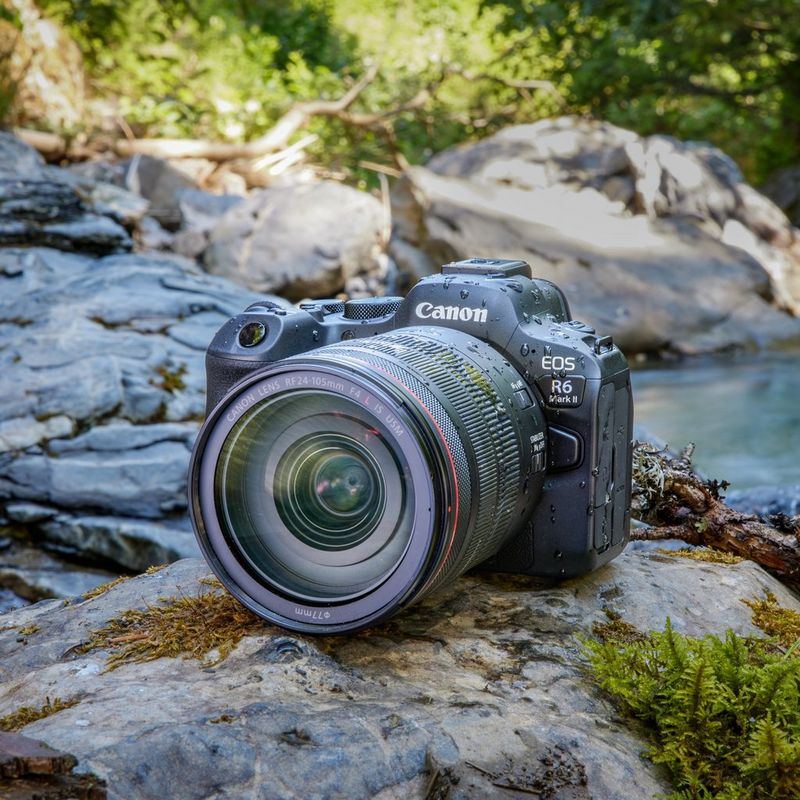 Canon EOS R6 Mark II spiegellose Kamera, Schwarz + Rucksack + SD-Karte+ Ersatzakku Produkt mit Objektiv auf Steinen neben einem See