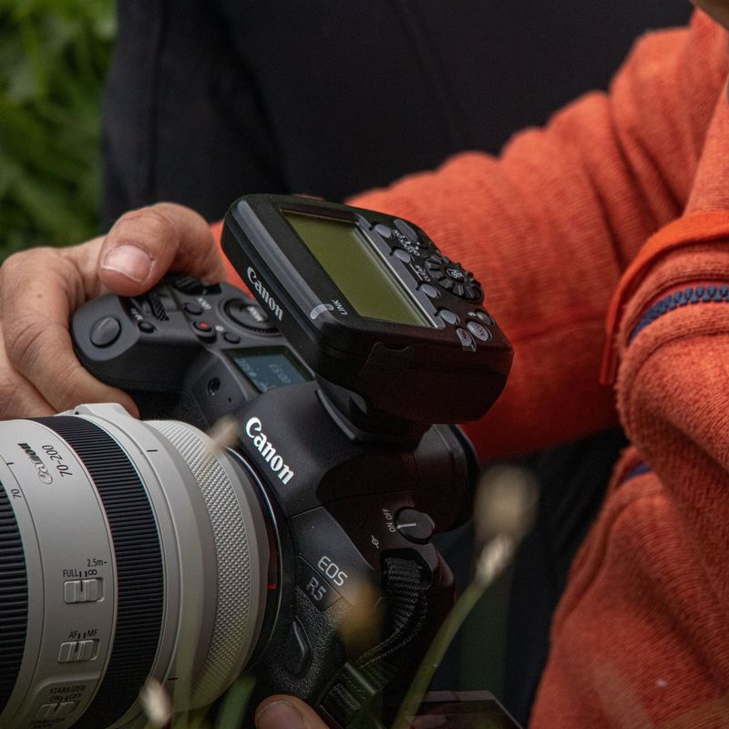Canon Speedlite Transmitter ST-E3-RT(Ver.2) 0 Man looking at the transmitter attached to a camera
