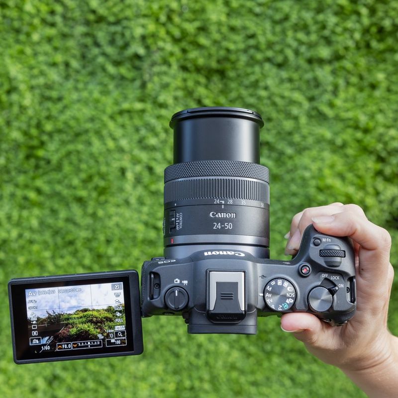 Canon EOS R8 spiegellose Kamera (Gehäuse), Schwarz + RF 85mm Macro IS STM Objektiv + RF 24-50mm IS STM Objektiv Eine Person, die sich etwas auf dem eingeklappten Bildschirm der Kamera ansieht
