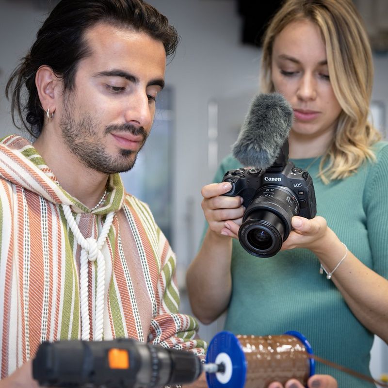 Canon EOS R8 spiegellose Kamera (Gehäuse), Schwarz + RF 85mm Macro IS STM Objektiv + RF 24-50mm IS STM Objektiv Eine Frau, die ein Video mit einer Kamera, einem Objektiv und einem Mikrofon aufnimmt