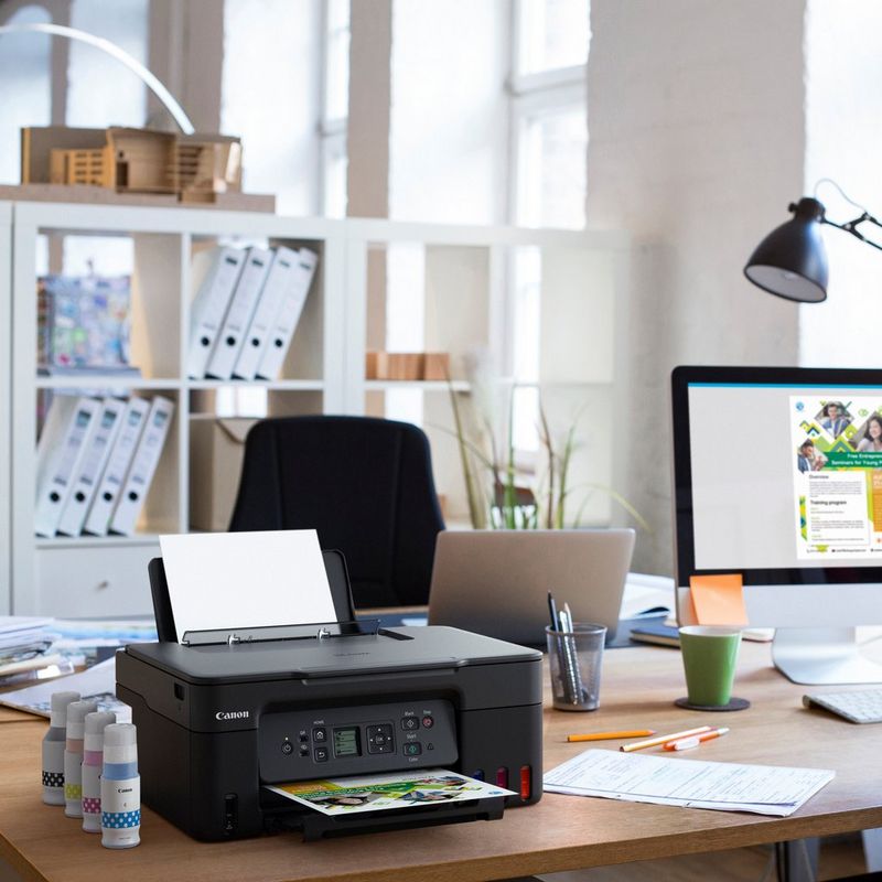 Canon PIXMA G3570 WLAN 3-in-1 MegaTank Farb-Multifunktionssystem mit nachfüllbaren Tintentanks , Schwarz Produkt auf einem Schreibtisch mit Tintenflaschen