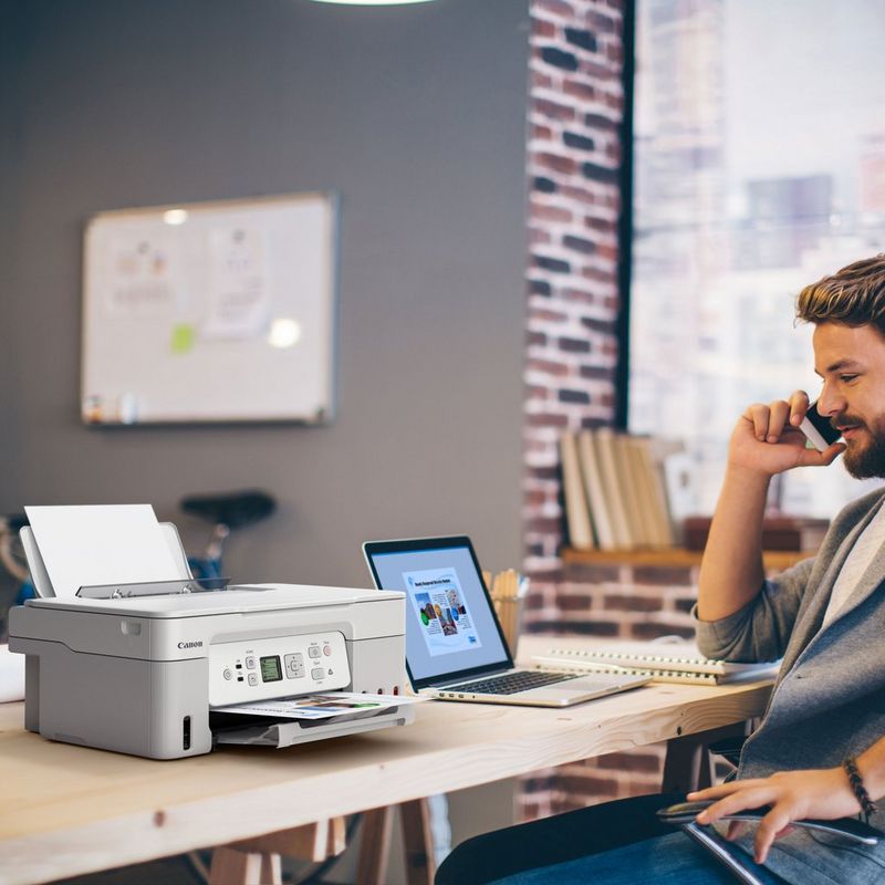 Canon PIXMA G3571 MegaTank 3-in-1 Farb-Multifunktionssystem mit WLAN und nachfüllbaren Tintentanks, Weiß Produkt auf einem Schreibtisch, an dem ein Mann telefoniert