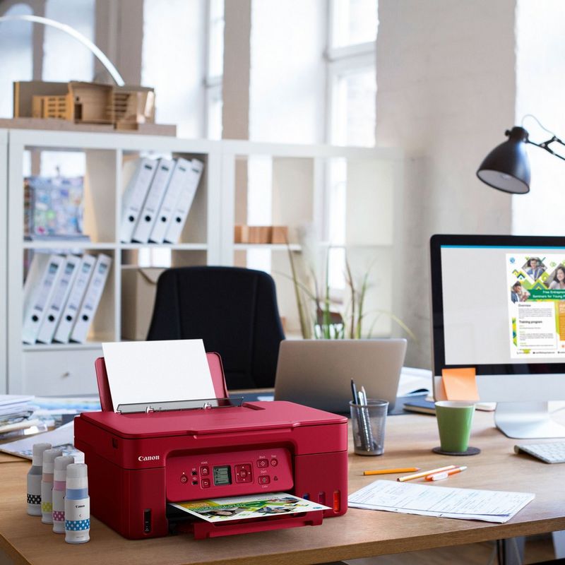 Canon PIXMA G3572 WLAN 3-in-1-Farb-Multifunktionssystem mit nachfüllbarem MegaTank, Rot Produkt auf einem Schreibtisch mit Tintenflaschen