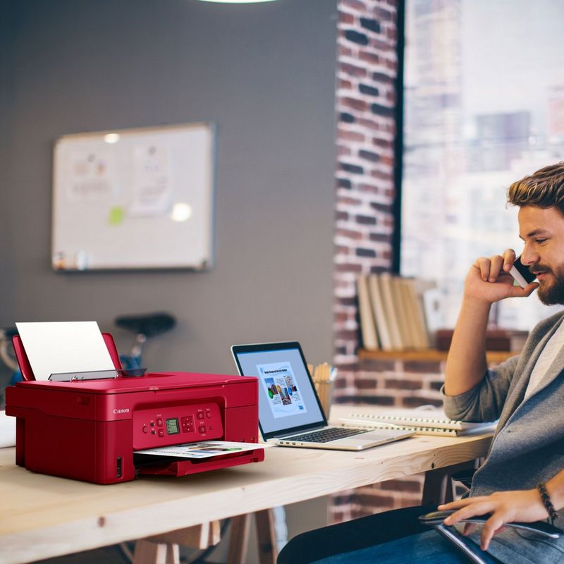 Canon PIXMA G3572 WLAN 3-in-1-Farb-Multifunktionssystem mit nachfüllbarem MegaTank, Rot Produkt auf einem Schreibtisch, an dem ein Mann telefoniert