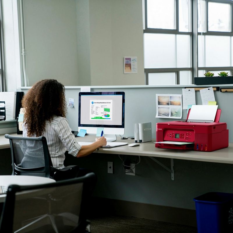 Canon PIXMA G3572 WLAN 3-in-1-Farb-Multifunktionssystem mit nachfüllbarem MegaTank, Rot Produkt auf einem Schreibtisch, an dem eine Frau an einem Computer arbeitet