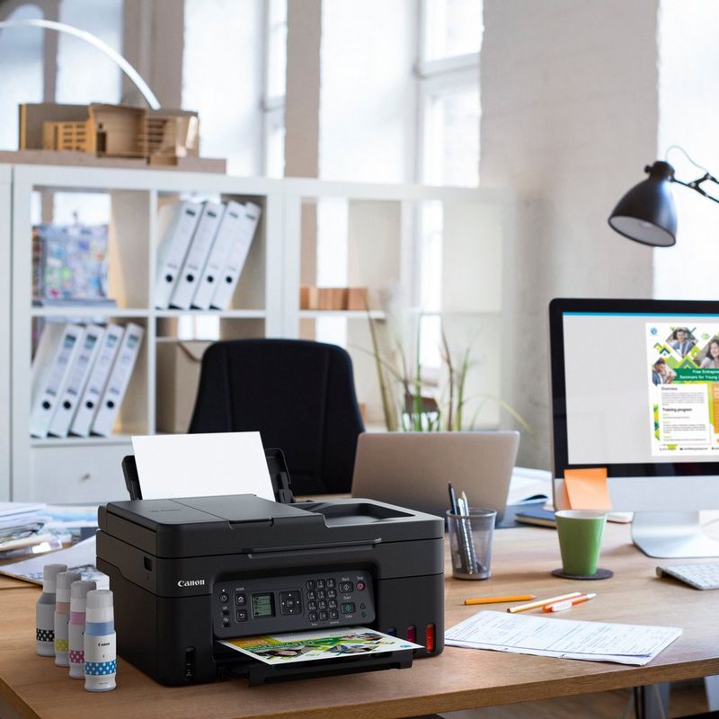 Canon PIXMA G4570 MegaTank Farb-Tintenstrahl-Multifunktionssystem mit WLAN und nachfüllbaren Tinten Produkt auf einem Schreibtisch mit Tintenflaschen