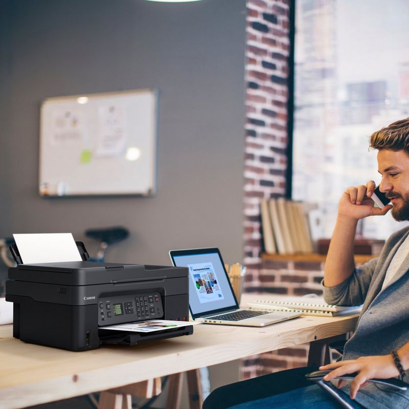 Canon PIXMA G4570 MegaTank Farb-Tintenstrahl-Multifunktionssystem mit WLAN und nachfüllbaren Tinten Produkt auf einem Schreibtisch, an dem ein Mann telefoniert