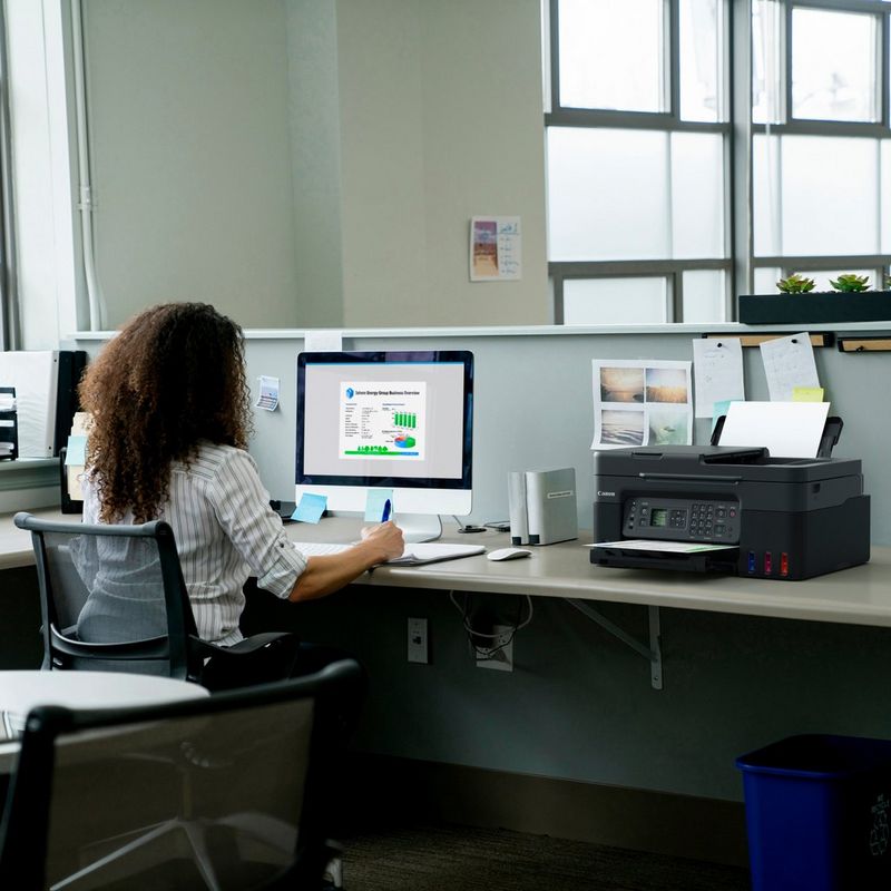 Canon PIXMA G4570 MegaTank Farb-Tintenstrahl-Multifunktionssystem mit WLAN und nachfüllbaren Tinten Produkt auf einem Schreibtisch, an dem eine Frau an einem Computer arbeitet