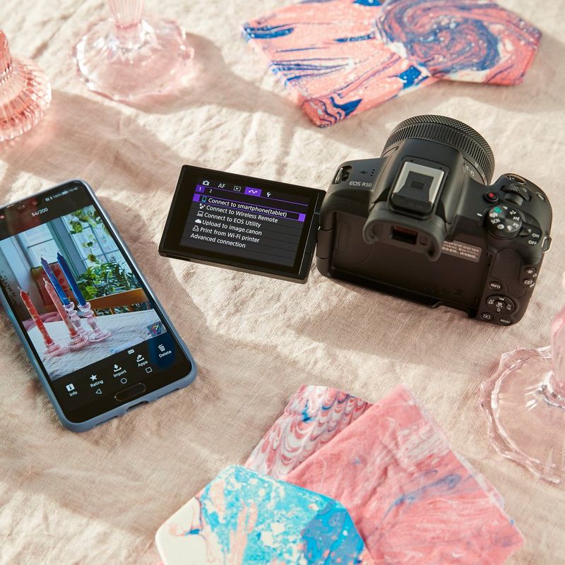 Canon EOS R50 spiegelloses Kameragehäuse, Schwarz Produkt neben einem Telefon