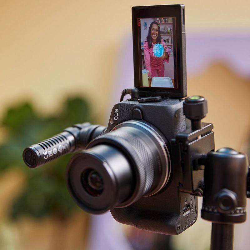 Canon EOS R50 spiegelloses Kameragehäuse Schwarz Vlogger Kit Produkt auf einem Stativ mit Mikrofon und offenem Bildschirm
