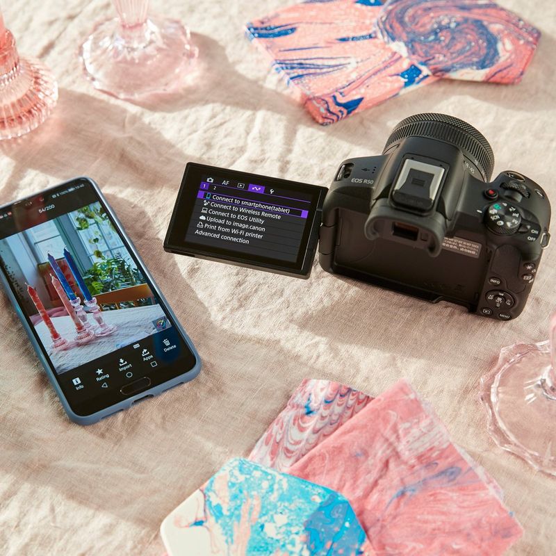 Canon EOS R50 spiegellose Kamera, Schwarz + RF-S 18-45mm F4.5-6.3 IS STM + Rucksack + SD-Karte + Ersatzakku Produkt neben einem Telefon