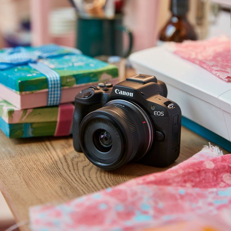 Canon EOS R50 spiegellose Kamera, Schwarz + RF-S 18-45mm F4.5-6.3 IS STM + Rucksack + SD-Karte + Ersatzakku Produkt auf Schreibtisch mit Geschenken