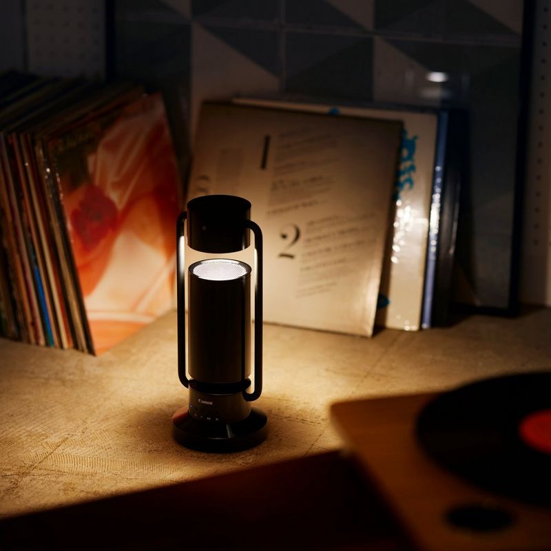 Canon Leuchte & Lautsprecher ML-A: drahtlose Bluetooth Lautsprecher Lampe aus Aluminium - Schwarz Produkt mit eingeschalteter Lampe auf einem Regal