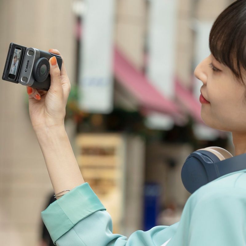 PowerShot-V10 Frau, die das Produkt seitlich mit aufgeklapptem Display hält, während sie einen Vlog aufnimmt