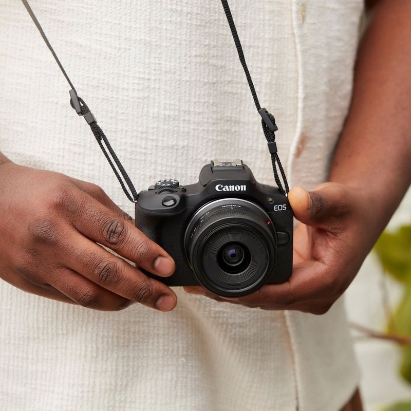 Canon EOS R100 spiegelloses Kamera Produkt hängt mit einem Tragegurt an einem Mann