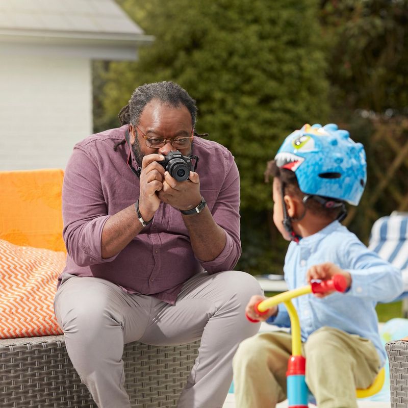 Canon EOS R100 spiegelloses Kamera Mann, der draußen ein Foto von einem Baby aufnimmt
