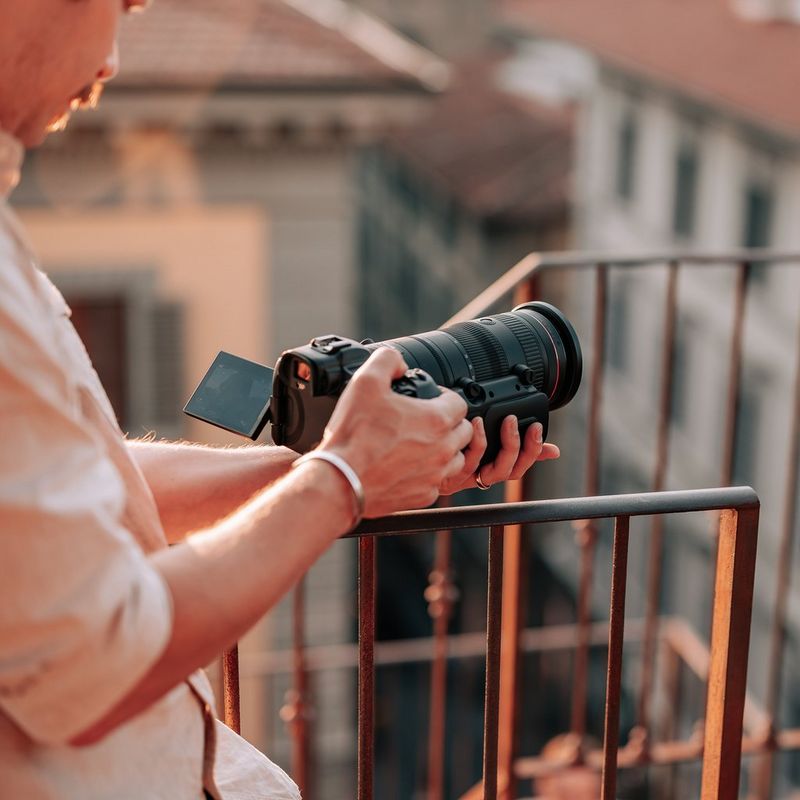 Canon Power Zoom Adapter PZ-E2 Mann, der auf einen Kamerabildschirm blickt, während das Produkt an einem Objektiv angebracht ist