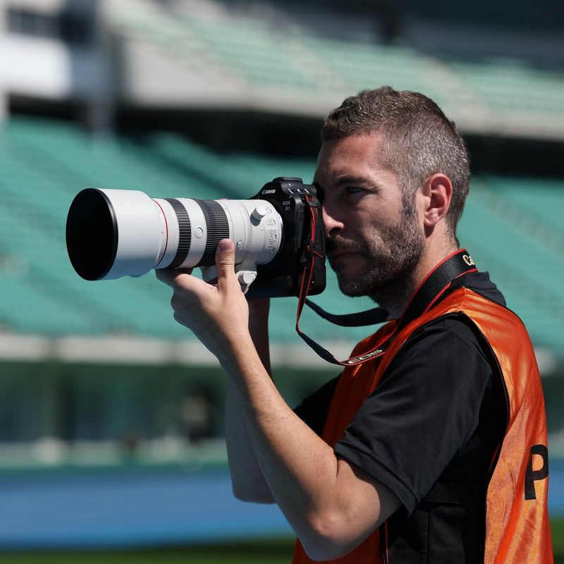 Canon RF 70-200mm F2.8L IS USM Z Objektiv, weiß Mann, der ein Foto auf einem Sportplatz knipst