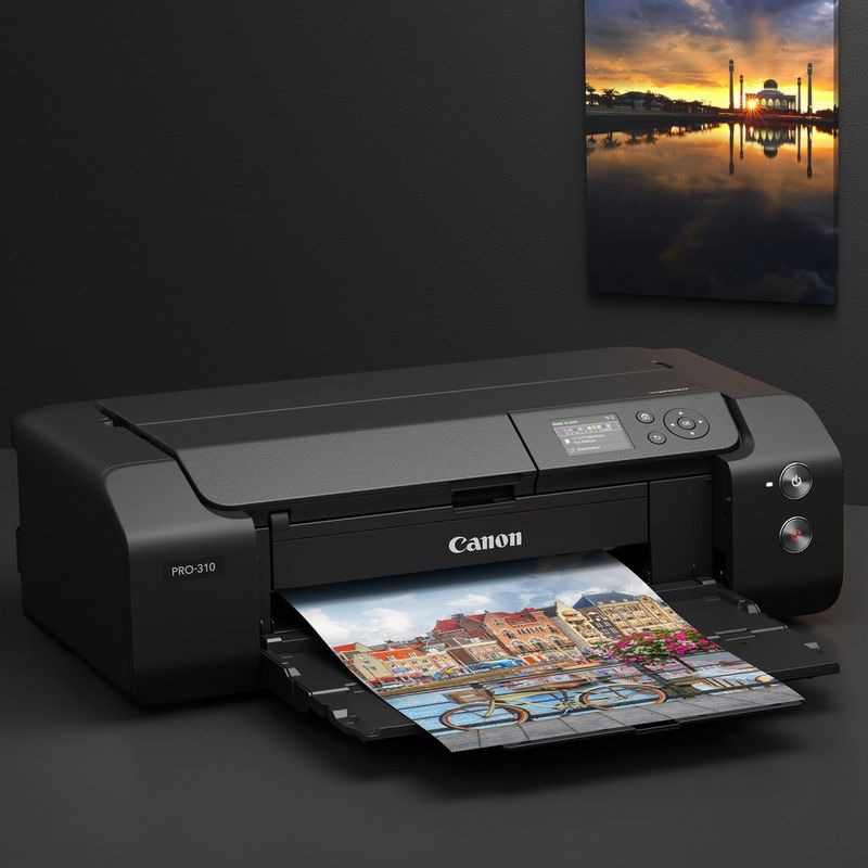 Canon imagePROGRAF PRO-310 A3+ Printer Product Front Slant View kept on table with printouts on the wall