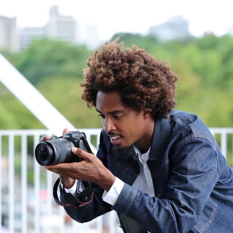 Canon RF 16-28mm F2.8 IS STM Objektiv Mann, der ein Foto vor einem städtischen Hintergrund knipst